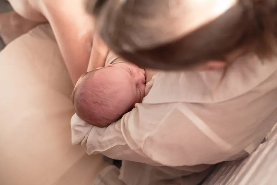 Una mamá sostiene a su bebé recién nacido mientras lo amamanta.