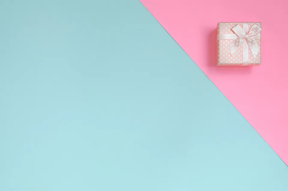 Cajita de regalo rosada sobre fondo pastel celeste y rosado.